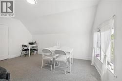 Carpeted room with sloped ceilings and a window featuring white trim - 