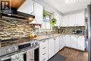 Kitchen featuring white cabinetry with dark hardware, a mosaic tile backsplash, and light-toned countertops - 103 Mcanulty Boulevard Unit# Upper, Hamilton, ON 