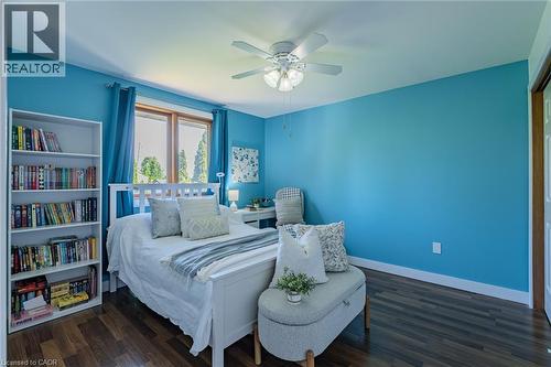 Bedroom featuring wood-finish flooring, a ceiling fan with integrated lighting, and a large window with white trim - 141 Lynndale Road, Simcoe, ON 