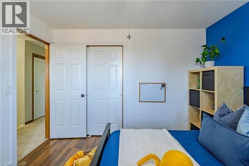 Bedroom featuring wood-finish flooring, two paneled closet doors, and a partial accent wall - 141 Lynndale Road, Simcoe, ON 