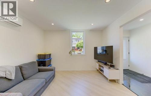 Bright interior space featuring light wood-finish flooring, recessed lighting, and a white wall-mounted mini-split HVAC unit - 11 Davidson Street, Cambridge, ON 