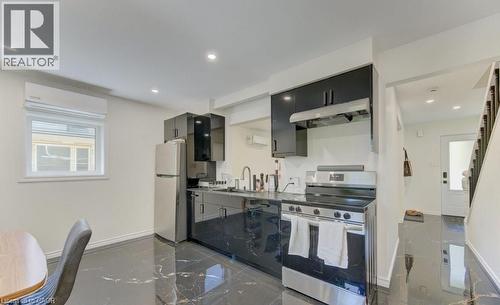 Modern kitchen featuring sleek black cabinetry, stainless steel appliances, and a dark marble-patterned flooring - 11 Davidson Street, Cambridge, ON 