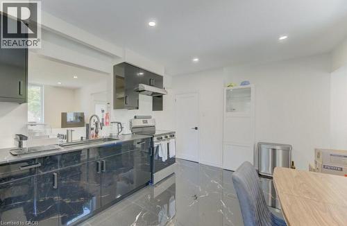 Kitchen featuring black cabinetry, stainless steel appliances, black countertops, and a single-basin sink with a pull-down faucet - 11 Davidson Street, Cambridge, ON 