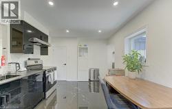 Contemporary kitchen featuring high-gloss black cabinetry, dark stone-finish countertops, stainless steel appliances, and recessed lighting - 