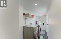 Functional laundry area featuring white walls, recessed lighting, and dark tile flooring - 
