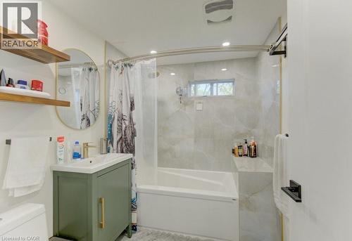 Contemporary bathroom featuring a white soaking tub with integrated shelving, light-toned patterned tile surround, and a compact window - 11 Davidson Street, Cambridge, ON 
