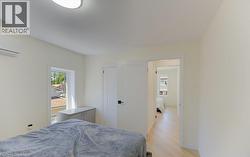 Bright room featuring light wood-finish flooring, a contemporary ceiling light fixture, a window with exterior views, and an internal entry door - 