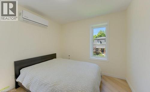 Light wood-finish flooring, a wall-mounted mini-split HVAC unit, and a single window with white trim - 11 Davidson Street, Cambridge, ON 
