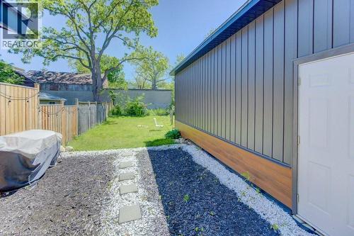 Landscaped backyard featuring a grass lawn, wood fencing, and a stone paver pathway - 11 Davidson Street, Cambridge, ON 