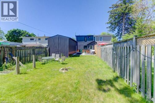 Expansive rear yard featuring green lawn, privacy fencing, and a detached shed - 11 Davidson Street, Cambridge, ON 