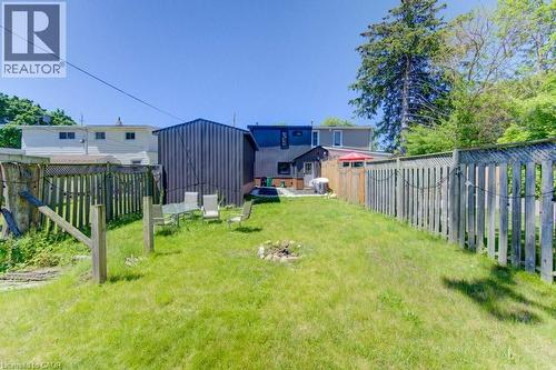 Expansive grassy backyard featuring a fire pit, wood fencing, and a detached shed - 11 Davidson Street, Cambridge, ON 