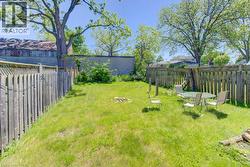 Expansive grassy yard area with mature trees and wood fencing - 