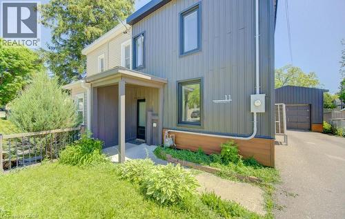 Contemporary-style residence featuring vertical siding, dark trim windows, a covered front porch, and an attached garage with a dark paneled door - 11 Davidson Street, Cambridge, ON 