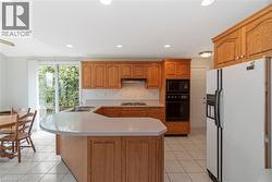 Kitchen featuring wood cabinetry with ample storage, a built-in wall oven and microwave, a cooktop, and a double sink - 