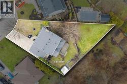 Expansive property featuring a grey shingle roof, a paved driveway, and a spacious green lawn - 