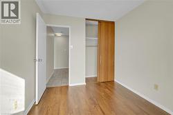 Room featuring wood-finish flooring, light-toned walls, and a sliding wood-panel closet door - 