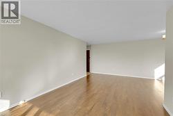 Spacious room featuring wood-finish flooring, light neutral wall paint, and a textured white ceiling - 