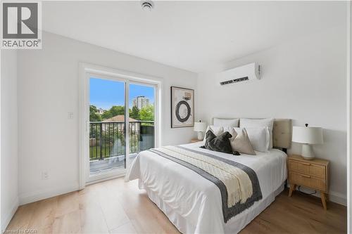 Bedroom featuring light wood-finish flooring, white walls, and a sliding glass door leading to a balcony with black metal railings - 60 Arlington Boulevard Unit# 3, Kitchener, ON 