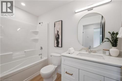 Bathroom featuring a white vanity with a stone-finish countertop, an undermount sink, and a circular mirror - 60 Arlington Boulevard Unit# 3, Kitchener, ON 