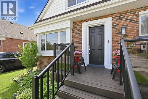 Brick and siding exterior featuring a multi-paneled black entry door with white trim, a front porch with composite decking and black railings, and a bay window - 18 Ipswich Place, Hamilton, ON 