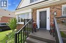 Brick and siding exterior featuring a multi-paneled black entry door with white trim, a front porch with composite decking and black railings, and a bay window - 18 Ipswich Place, Hamilton, ON 