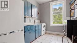 Kitchen featuring a white refrigerator, blue cabinetry with dark hardware, white tile backsplash, and a white oven/range - 