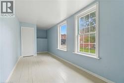 Room featuring two sash windows, light blue walls, and painted wood flooring - 