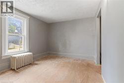 Room featuring a single-hung window with decorative trim, a cast-iron radiator, and light gray painted walls - 