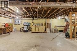 Unfinished basement with concrete flooring, exposed ceiling joists, and visible wiring - 