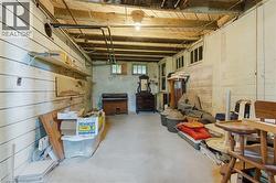 Exposed wooden ceiling beams above a concrete floor, with horizontal wood paneling on one wall - 