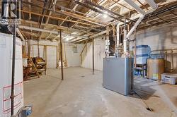 Unfinished basement featuring a concrete floor, exposed ceiling joists, and a hot water heater - 