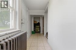 Entryway featuring tile flooring, a window with natural light, and a cast-iron radiator - 