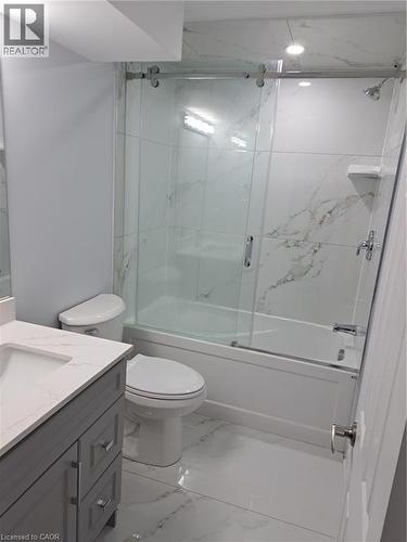 Bathroom featuring a white bathtub with a sliding glass door enclosure, a single vanity with a gray wood-finish cabinet, and a white countertop - 2240 Headon Road Unit# Lower, Burlington, ON 