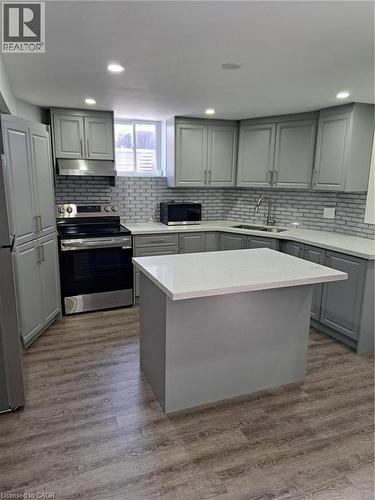 Contemporary kitchen featuring light gray cabinetry, white countertops, a subway tile backsplash, and wood-finish flooring - 2240 Headon Road Unit# Lower, Burlington, ON 