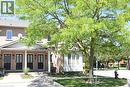 Brick facade townhome featuring black paneled front doors with glass inserts, covered entry porches, white gabled accents, and a mature shade tree - 2 Harbour Drive Unit# 17, Stoney Creek, ON 