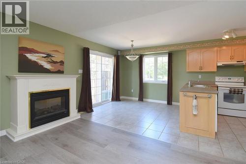 Living area with a white mantel fireplace, wood-finish flooring, and a sliding glass door - 2 Harbour Drive Unit# 17, Stoney Creek, ON 