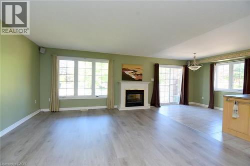 Spacious room featuring light wood-finish flooring, a white mantel fireplace, and multiple large windows - 2 Harbour Drive Unit# 17, Stoney Creek, ON 