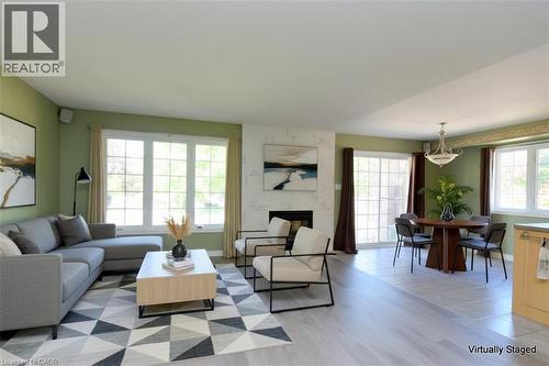 Open concept living and dining area featuring a fireplace with a light-toned surround, expansive windows, wood-finish flooring, and recessed lighting - 2 Harbour Drive Unit# 17, Stoney Creek, ON 