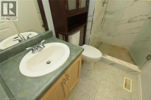 Bathroom featuring a vanity with an integrated sink, a glass-enclosed shower with white marble-effect wall tiles, and neutral-toned floor tiles - 2 Harbour Drive Unit# 17, Stoney Creek, ON 