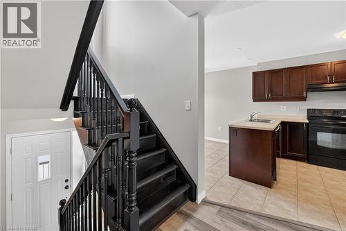Entryway featuring dark wood-finish staircase with balusters and a white paneled door - 7 Hepworth Crescent, Ancaster, ON 