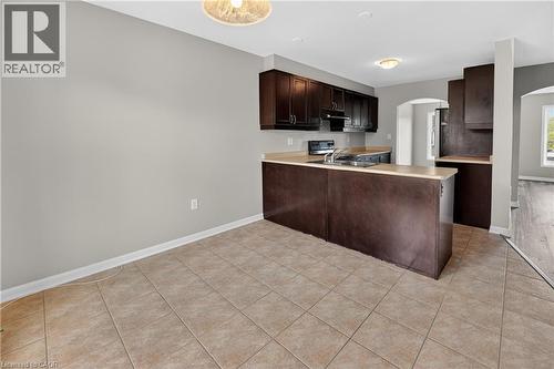 Kitchen featuring dark wood-finish cabinetry, light-toned countertops, and a stainless steel sink with a garbage disposal - 7 Hepworth Crescent, Ancaster, ON 
