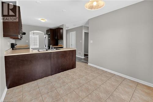 Kitchen area featuring tile flooring, dark wood-finish cabinetry, a stainless steel sink, light-colored countertops, and recessed lighting - 7 Hepworth Crescent, Ancaster, ON 