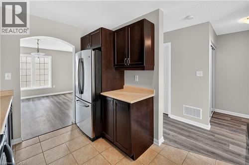 Kitchen area featuring tile flooring, dark wood cabinetry, and a stainless steel refrigerator - 7 Hepworth Crescent, Ancaster, ON 