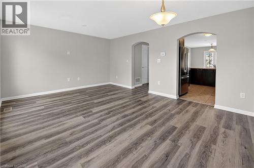 Spacious living area featuring wood-finish flooring, light gray wall paint, and white baseboards - 7 Hepworth Crescent, Ancaster, ON 