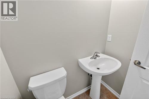Powder room featuring a white pedestal sink with chrome faucet, a white toilet, and neutral wall paint - 7 Hepworth Crescent, Ancaster, ON 