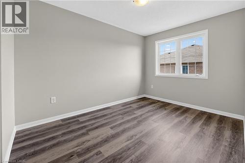 Room featuring wood-finish flooring, light grey painted walls, white baseboards, and a double-pane window with white trim - 7 Hepworth Crescent, Ancaster, ON 