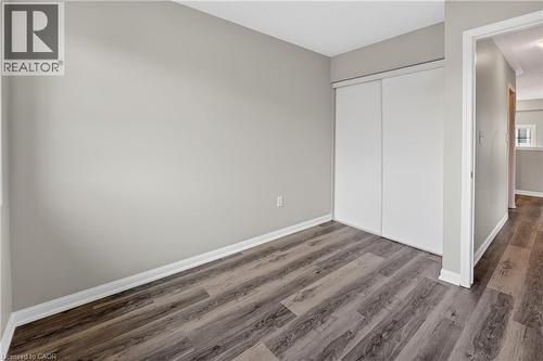 Room featuring wood-finish flooring, light grey painted walls, and white trim - 7 Hepworth Crescent, Ancaster, ON 