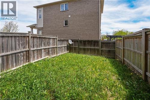 Enclosed backyard featuring a wood fence perimeter and a partially visible brick exterior - 7 Hepworth Crescent, Ancaster, ON 