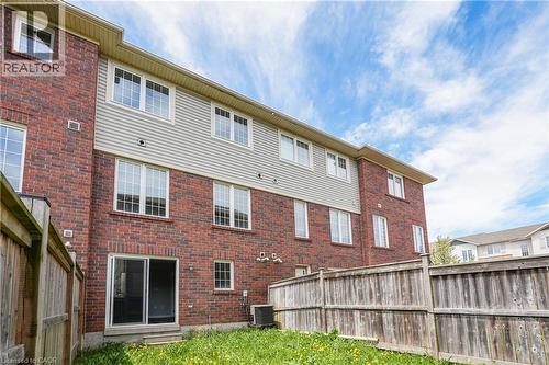 Rear exterior featuring a brick and siding facade, multiple white-framed windows, and a sliding glass door - 7 Hepworth Crescent, Ancaster, ON 