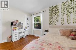 Hardwood flooring throughout featuring white trim and baseboards, a window with white casing, and a white paneled door - 